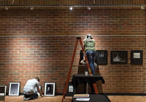  艺术与设计专业的学生周五晚上在两河休息室准备他们的画廊展览. 伍迪·迈尔斯摄